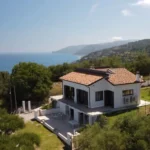 Vista aerea di una villa con tetto in tegole, immersa nel verde e affacciata sul mare della costa settentrionale siciliana.