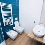 Secondo bagno con pareti blu petrolio, lavabo d’appoggio e sanitari moderni – Villa Giardino degli Ulivi
