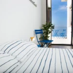 Camera con letto matrimoniale, sedie blu e terrazza affacciata sul mare – Villa Giardino degli Ulivi, Sicilia