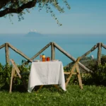 Tavolino con colazione su prato vista mare, con panorama sulle Isole Eolie, a Villa Giardino degli Ulivi.