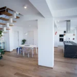 Cucina open space con isola in marmo, scala sospesa in legno e arredi moderni – Villa Giardino degli Ulivi, Sicilia
