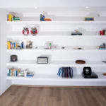 Libreria moderna a parete con libri, vinili, ceramiche e oggetti decorativi – Villa Giardino degli Ulivi, Sicilia