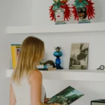 Dettaglio della libreria con decorazioni tipiche siciliane e ospite che osserva un vinile – Villa Giardino degli Ulivi, Sicilia