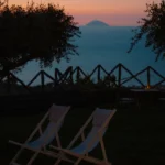 Due sdraio da giardino al tramonto con vista sull’isola di Alicudi, riprese dal giardino panoramico di Villa Giardino degli Ulivi a Capo d’Orlando, Sicilia.