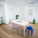 Sala da pranzo luminosa con sedie trasparenti e design moderno, pavimento in legno chiaro – Villa Giardino degli Ulivi, Sicilia